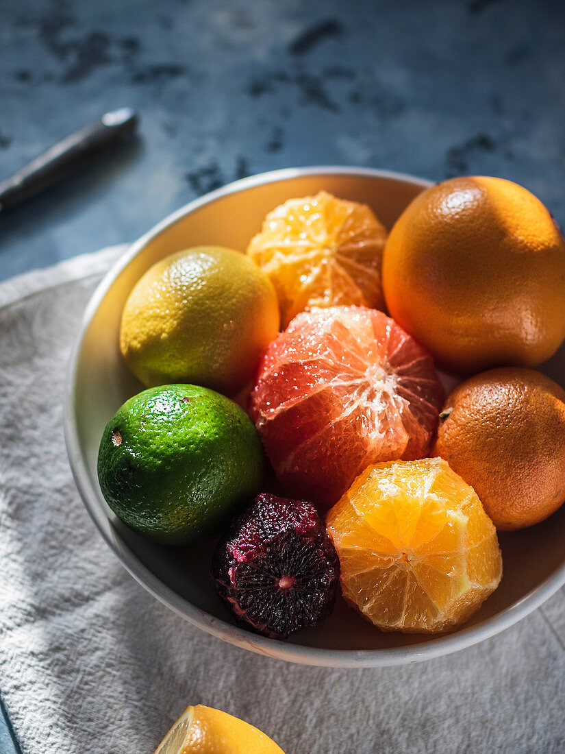 Citrus fruits in the bowl standing on the linen towel