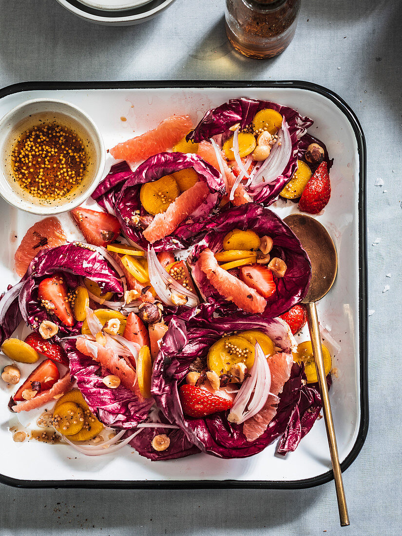 Radicchio salad with rainbow carrots, berries, fruits and hazelnuts served in white tray