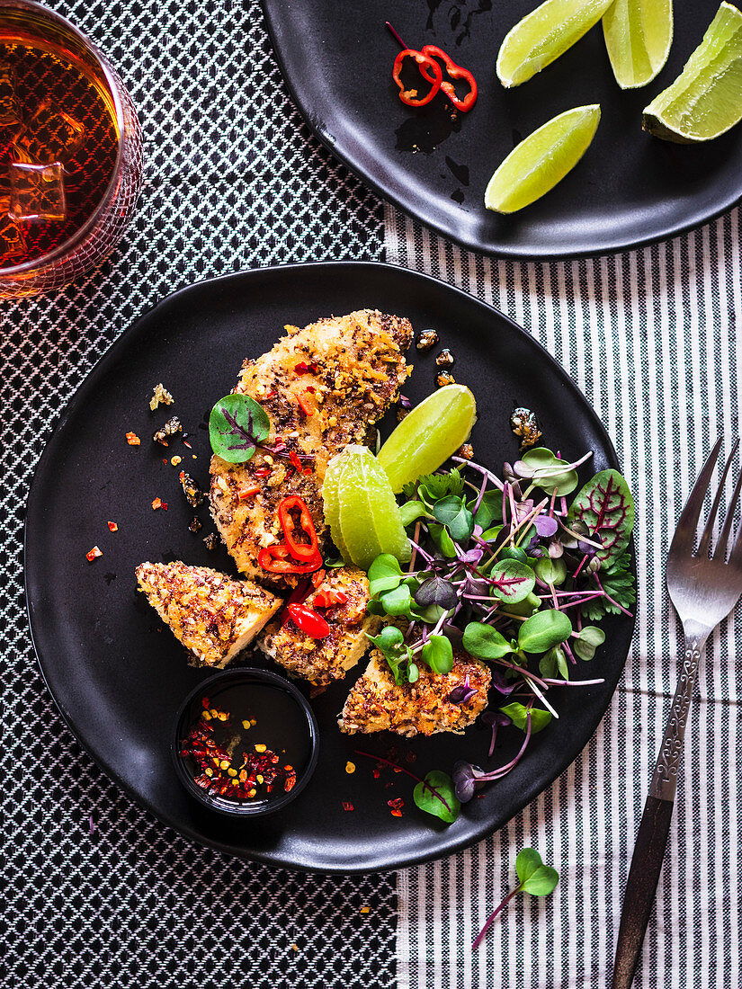 Chia Crusted Chicken Strips with microgreens served on a black plate