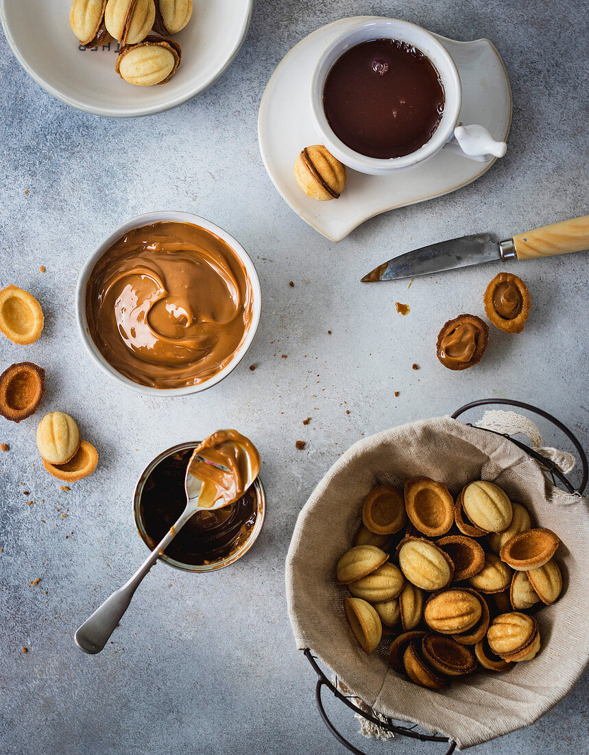 Walnut cookies in a basket with dulce de leche in a bowl and tea cup on gray background