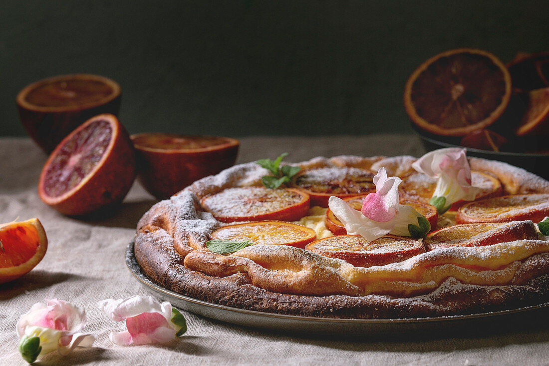 Flacher Käsekuchen mit sizilianischen Blutorangen dekoriert mit Essblüten
