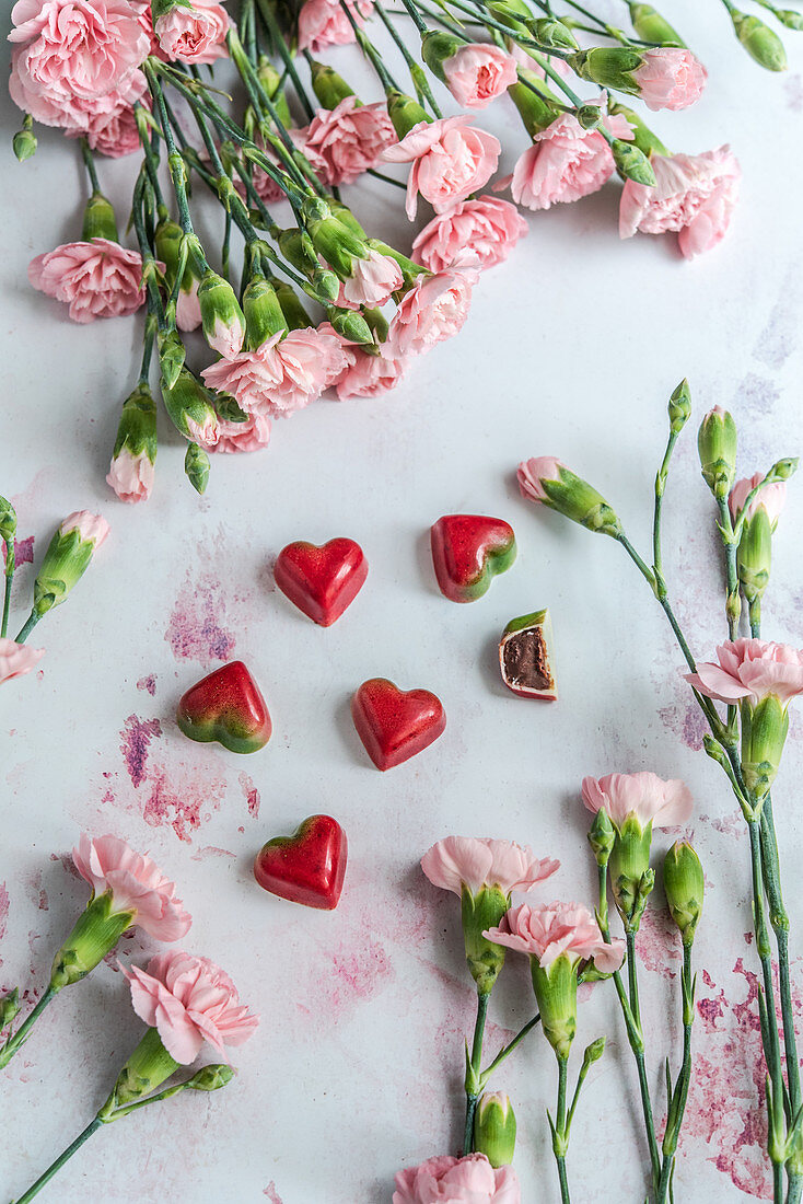 Schokoladen-Erdbeer-Pralinen in Herzform mit rosa Blüten