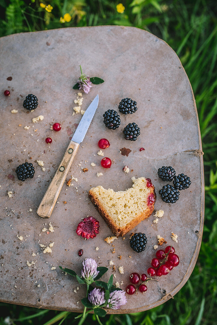 Angebissenes Stück Sommerkuchen mit Himbeeren, Brombeeren und Johannisbeeren