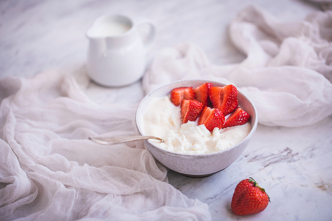 Ein Schälchen Hüttenkäse mit Sahne und Erdbeeren