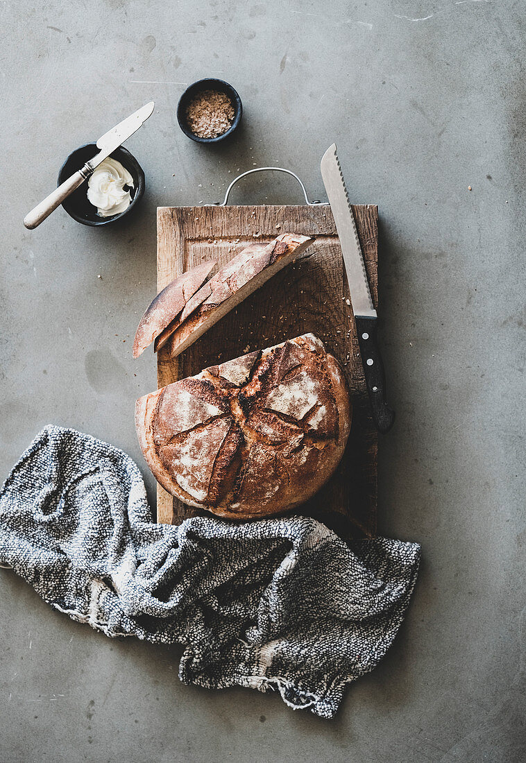 Sauerteigbrot, angeschnitten auf rustikalem Holzbrett (Aufsicht)