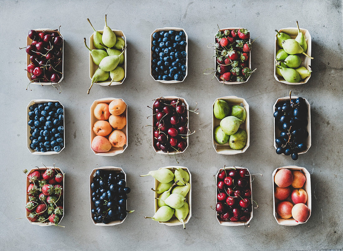 Summer fruit, berry assortment: Flat-lay of fresh strawberries, cherries, grape, blueberries, pears, apricots, figs in eco-friendly boxes