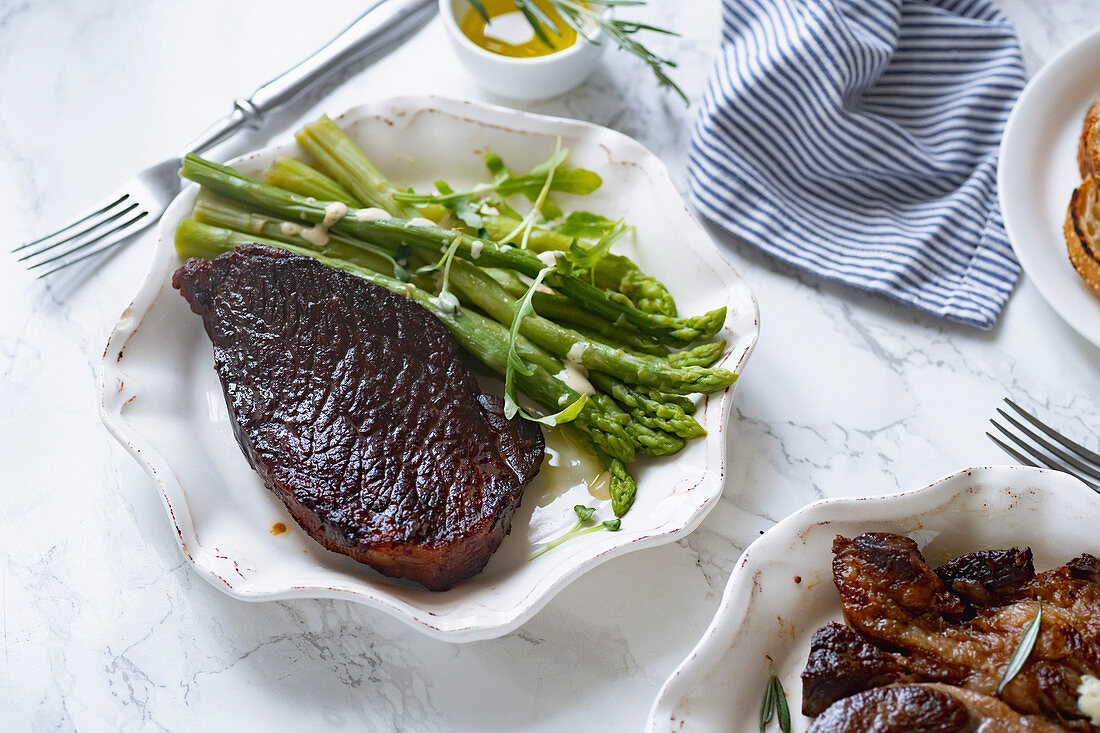 Cooked black angus prime beef steak with asparagus and cream mustard sauce