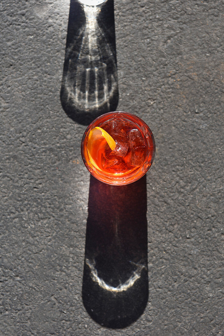 Negroni im Glas auf grauem Untergrund mit Schattenwurf