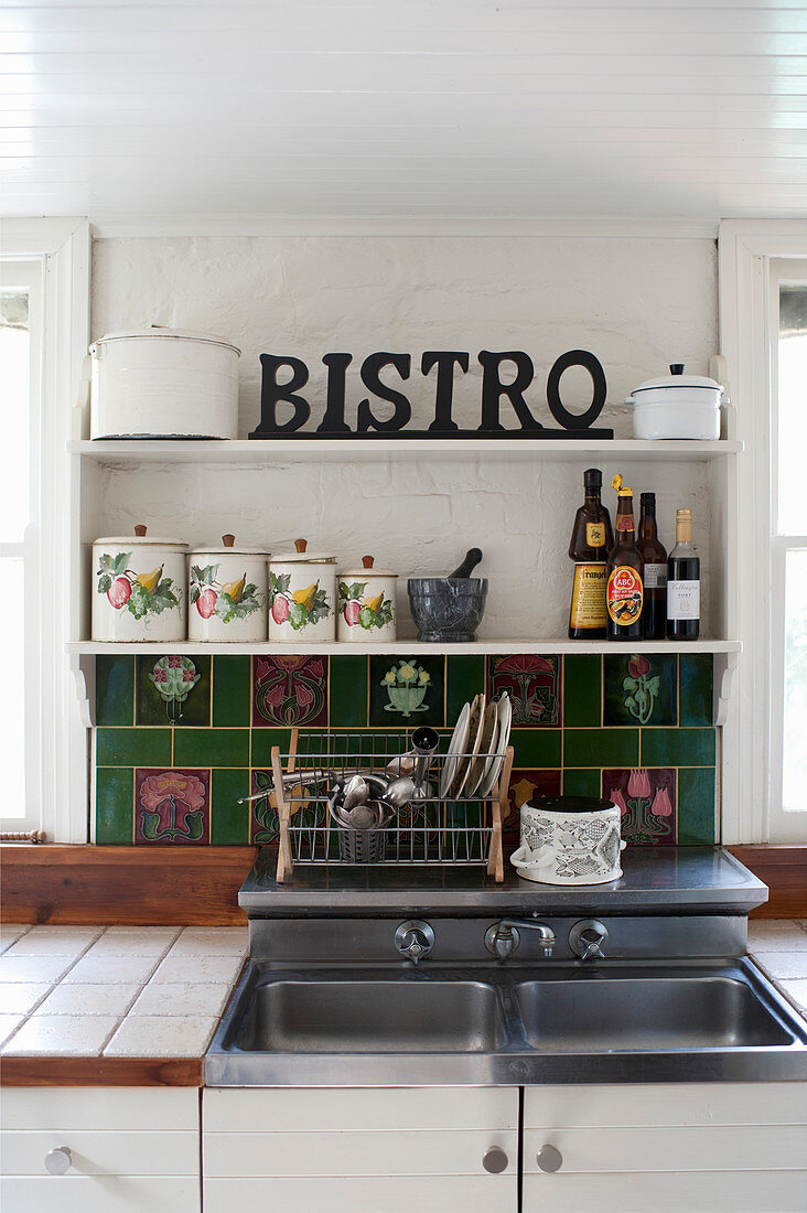 Spülbecken, darüber grüne Fliesen und Regale mit Vintage Vorratsdosen in der Küche