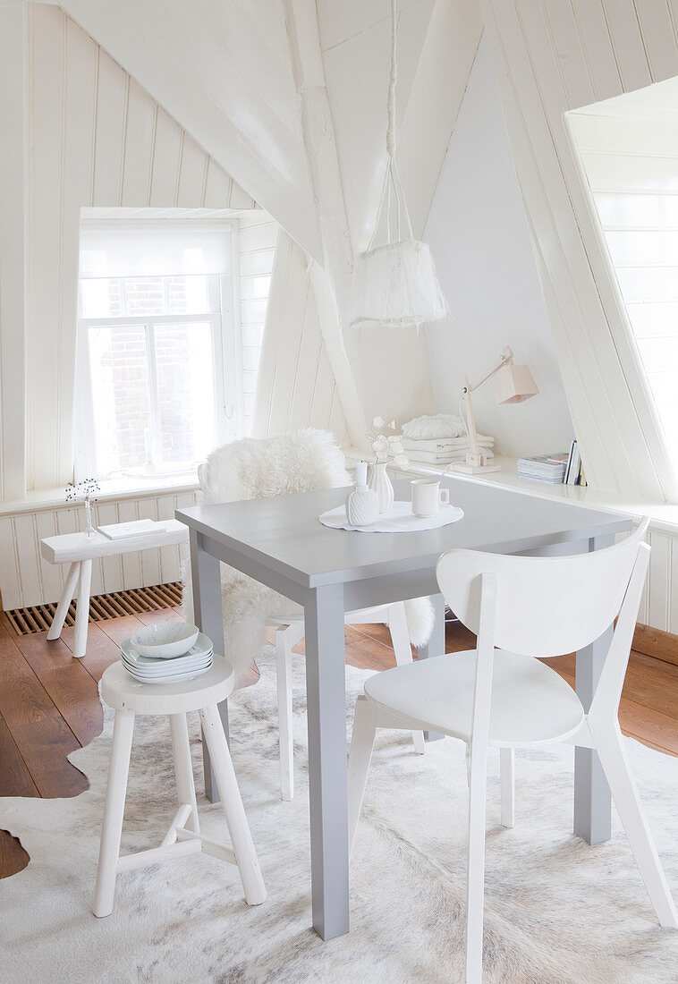 Small dining table and various chairs in white interior