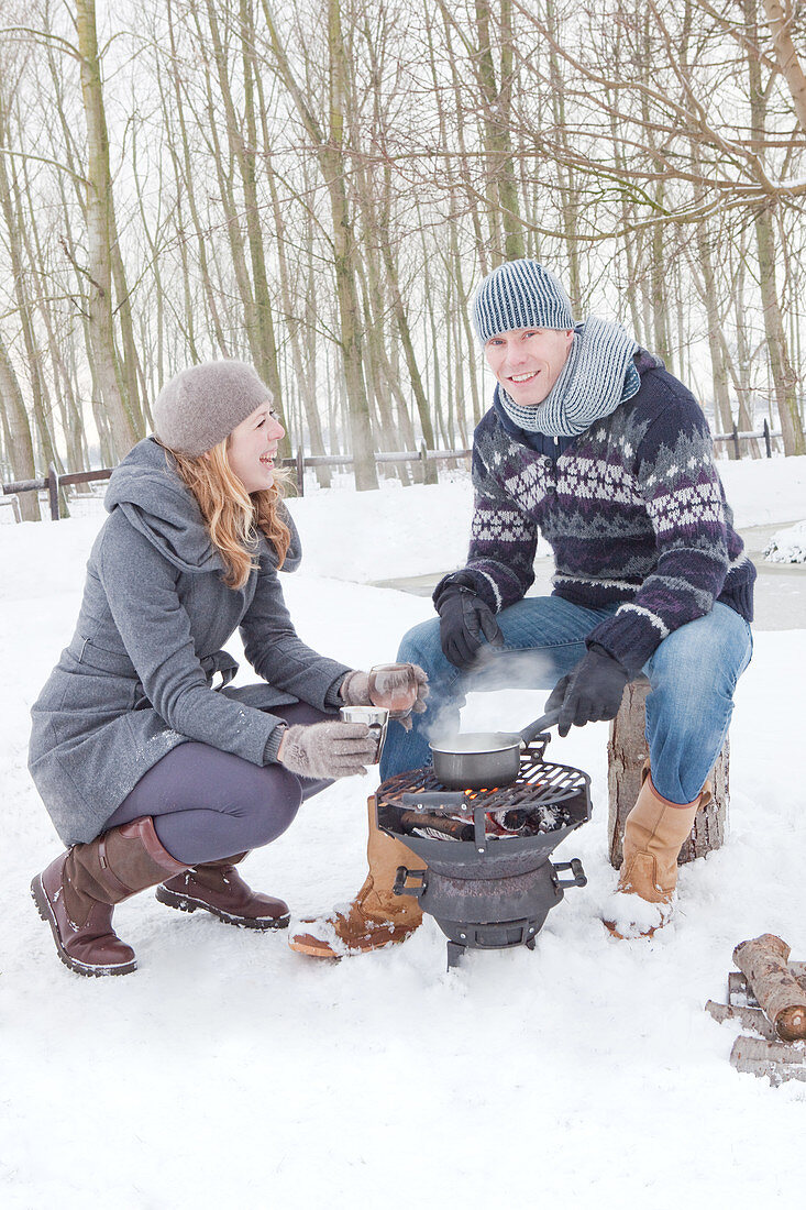 Couple cooking brazier in snowy landscape