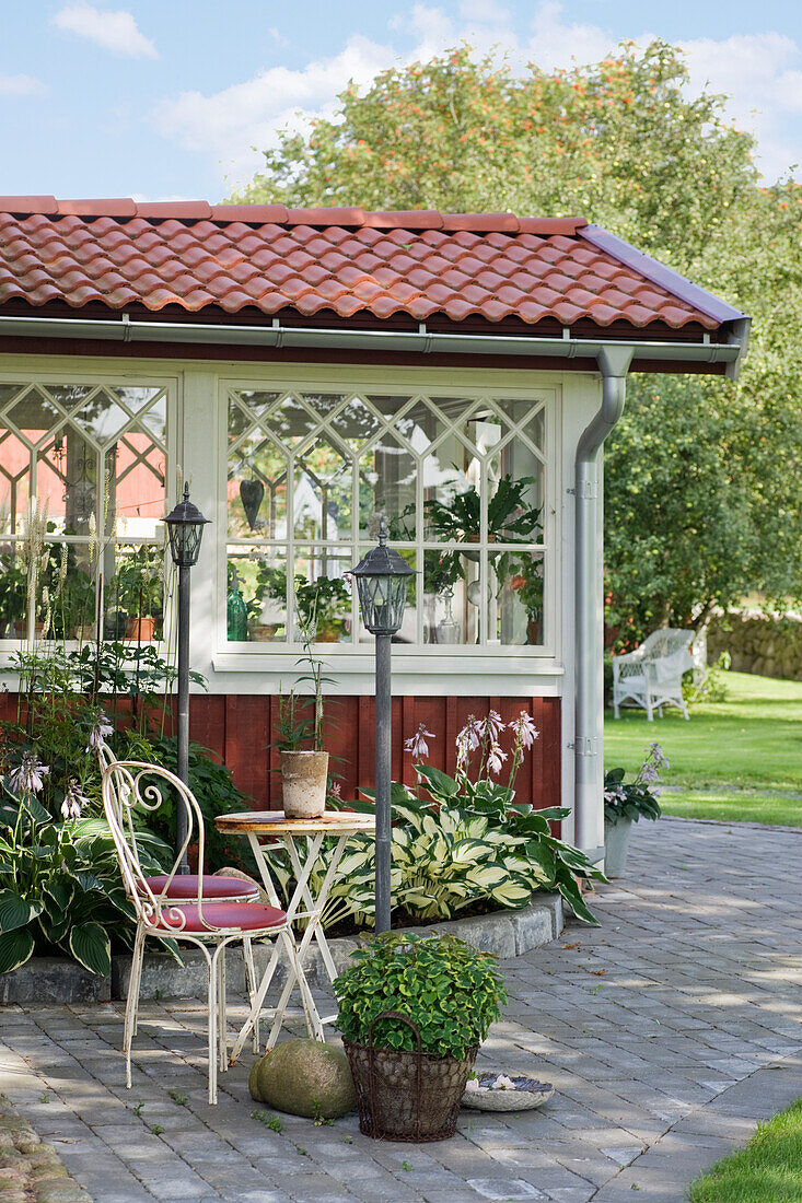 Schattenplatz mit nostalgischen Gartenstühlen neben Holzhaus