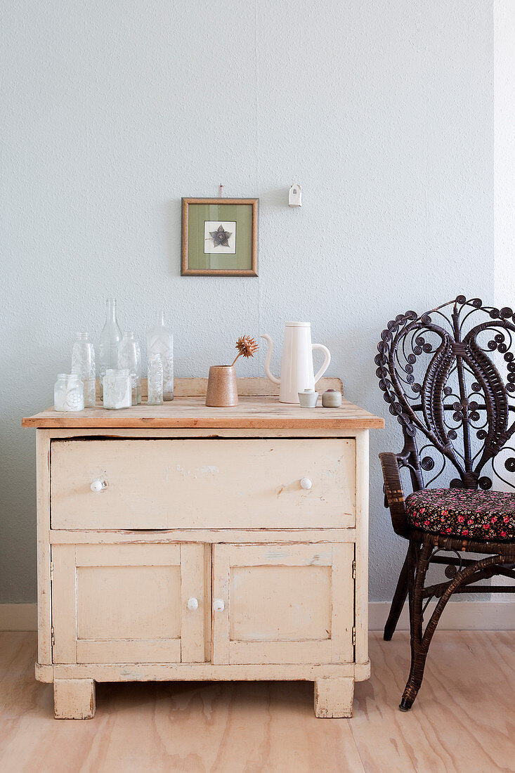 Ornate chair next to old cabinet with collection of vases