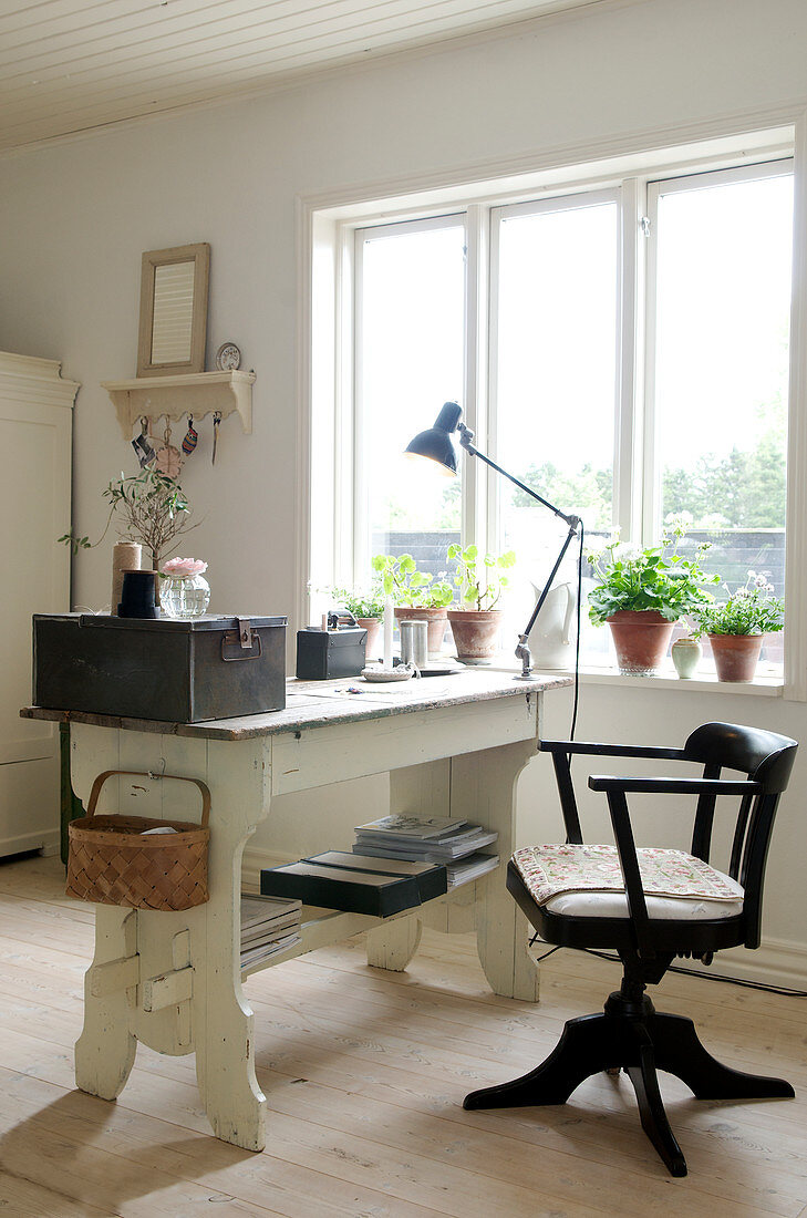 Old swivel chair and desk with vintage accessories next to window