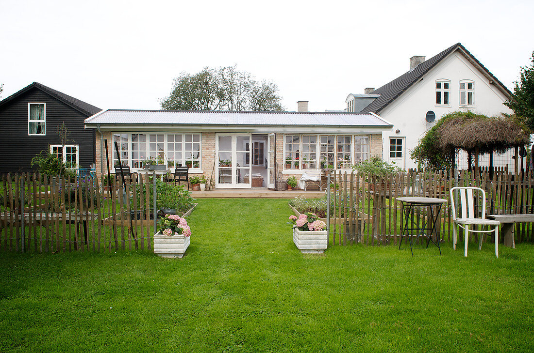 Eingang mit Pflanztrögen im Staketenzaun zum Garten und Haus