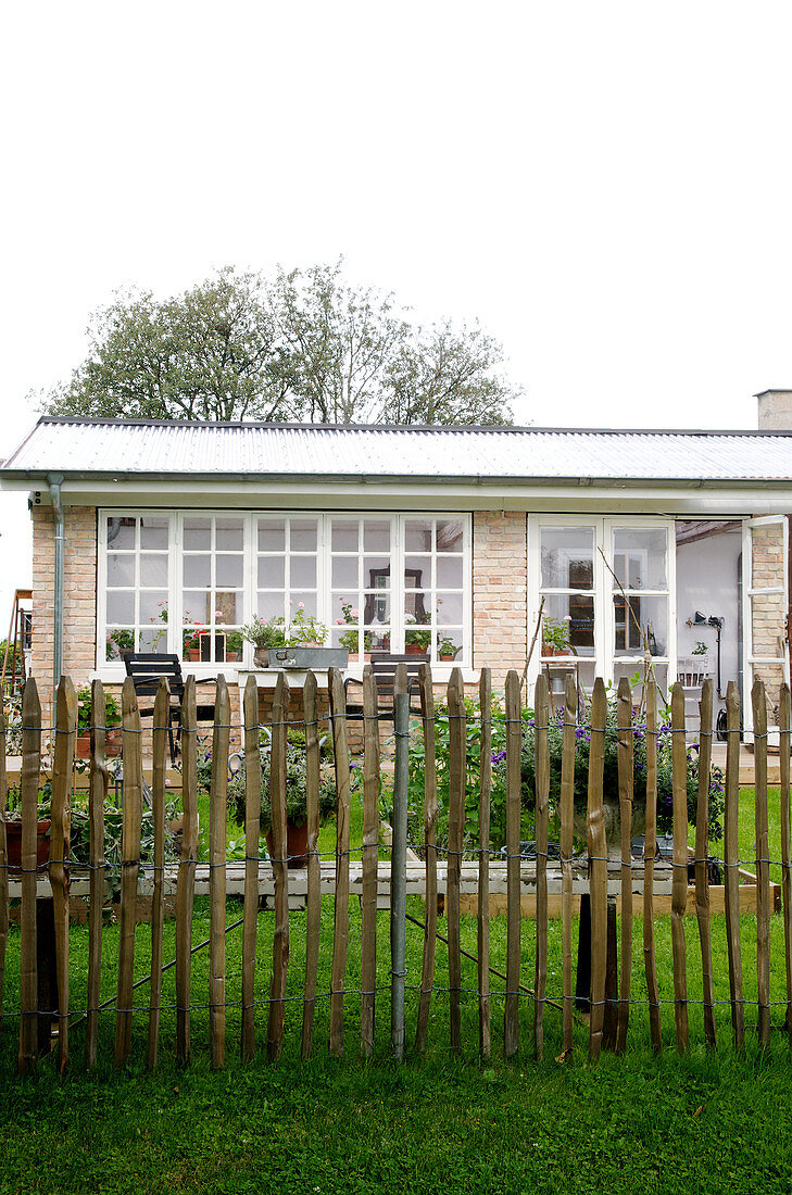 Staketenzaun vor dem Haus mit sommerlichem Garten