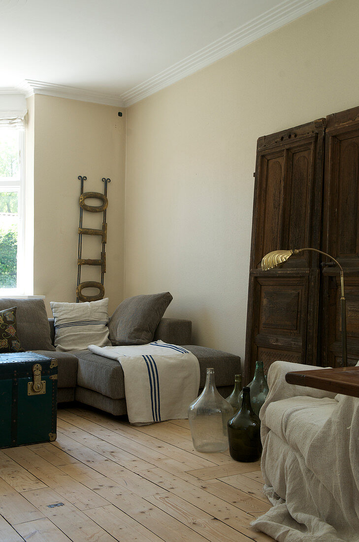 Living room in natural tones with an old door and wine jugs as decoration