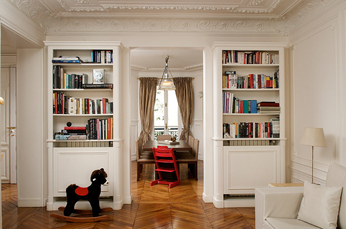 Klassisches Wohnzimmer mit Stuckdecke und Blick ins Esszimmer mit Kinderhochstuhl