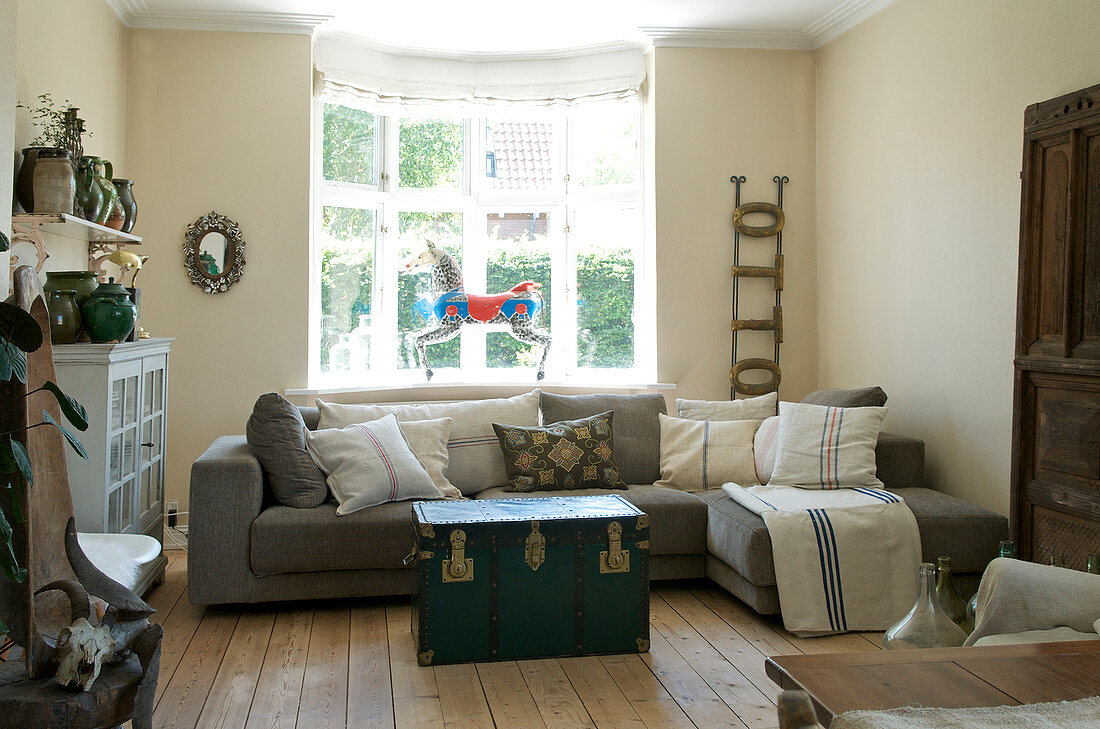 Graues Sofa und Truhe als Couchtisch im Wohnzimmer in Naturtönen