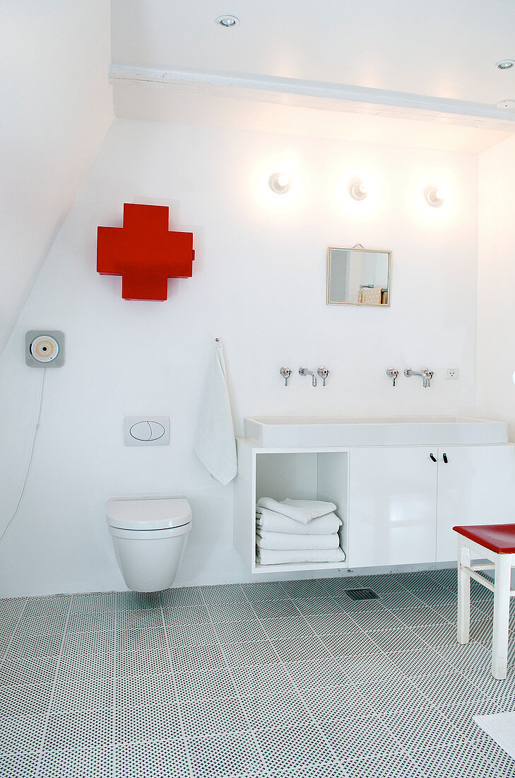 A medicine cabinet in a cross shape above the toilet in the modern bathroom