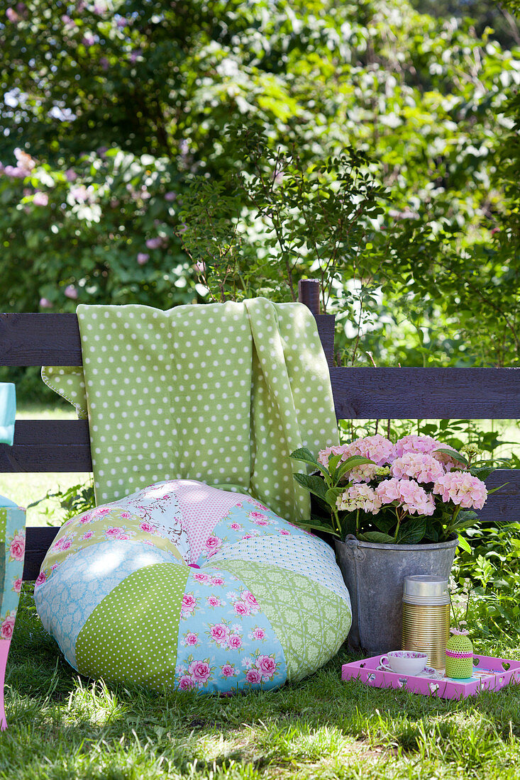 Rundes Patchworkkissen in Hellblau und Grün im Garten