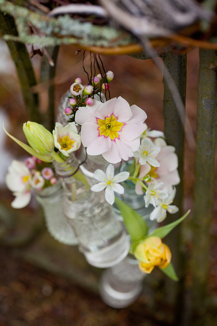 Arrangements of flowers in tiny bottles hung from wire