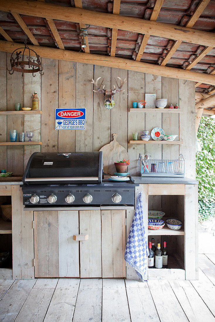 Outdoor kitchen on a covered terrace with a wooden wall