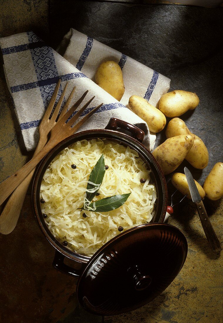 Sauerkraut im Steinguttopf von oben, Deko: frische Kartoffeln