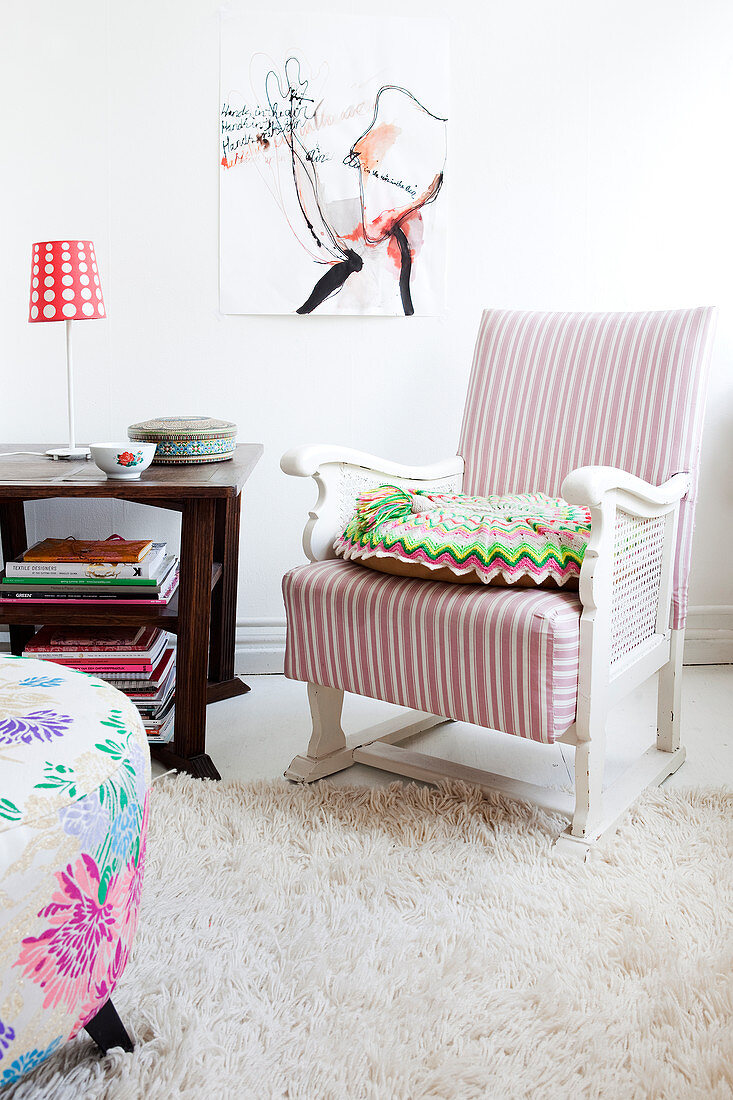 Antique armchair with white and pink striped upholstery next to a wooden side table