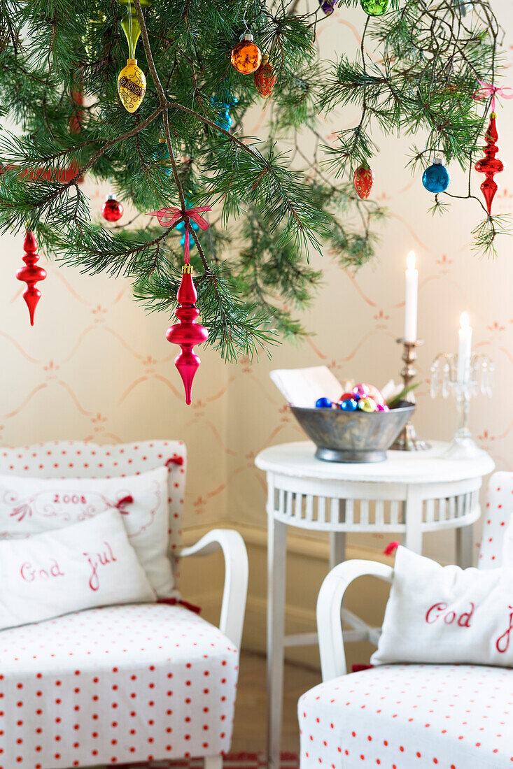 A pine tree decorated for Christmas, sitting area in the background