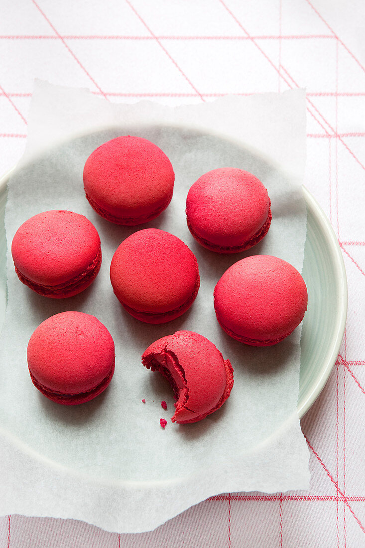 Red macarons on a plate, one bitten