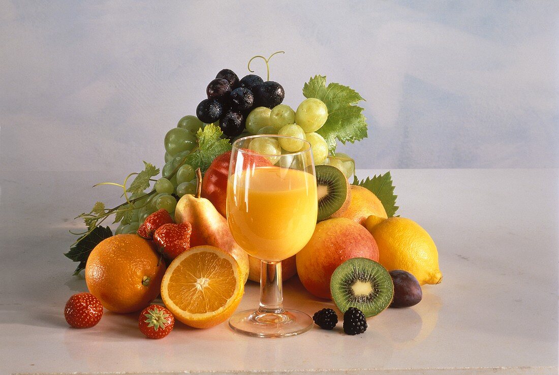 Ein Glas Orangensaft vor verschiedenem frischen Obst