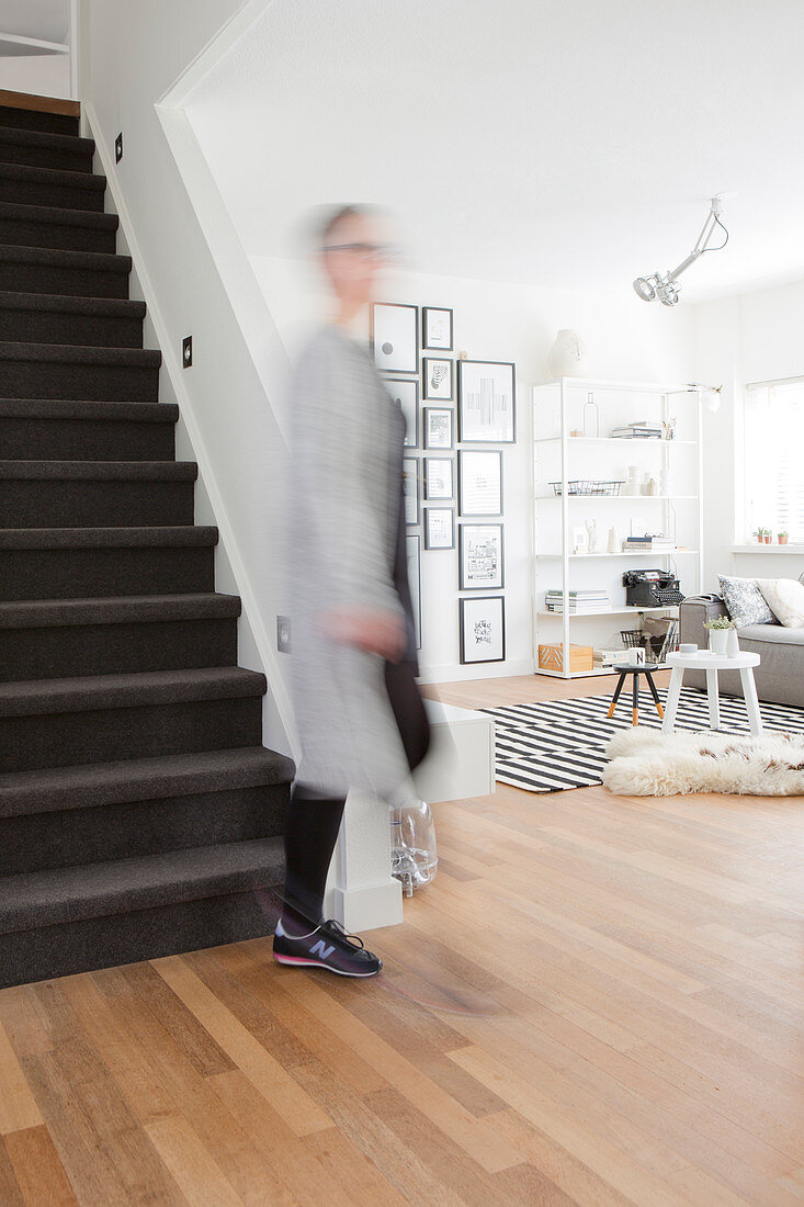 View past foot of staircase into living room decorated in black and white