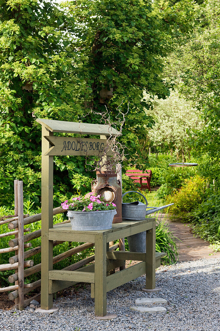 Old-fashioned wooden sales table, decorated with old zinc tub and watering can