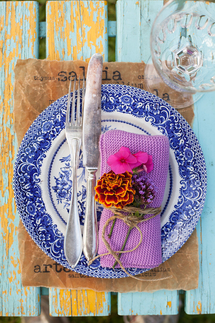 Napkin decorated with French marigold, phlox and verbena flowers on old plate