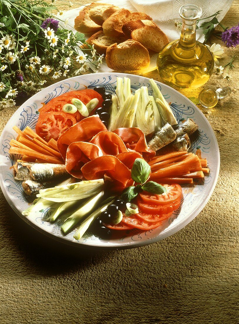Antipasto platter with vegetables, olives, sardines, ham