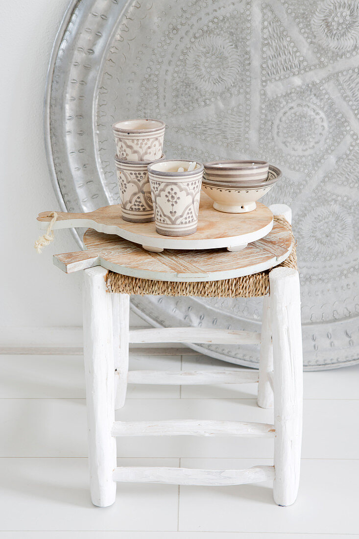 Wooden cutting boards with cups and bowls on a stool