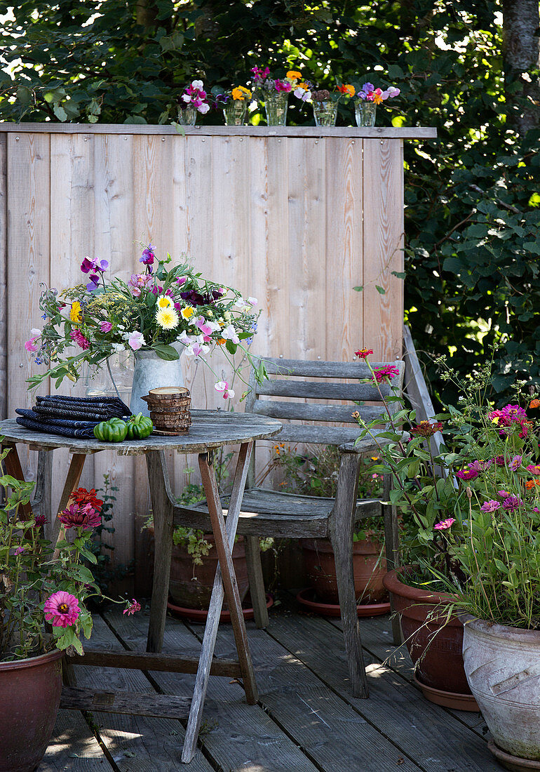 Rustic seat on the terrace with a wooden wall and summer flowers