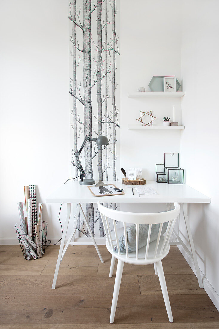 White desk and sprout chair in front of a strip of wallpaper with a forest motif