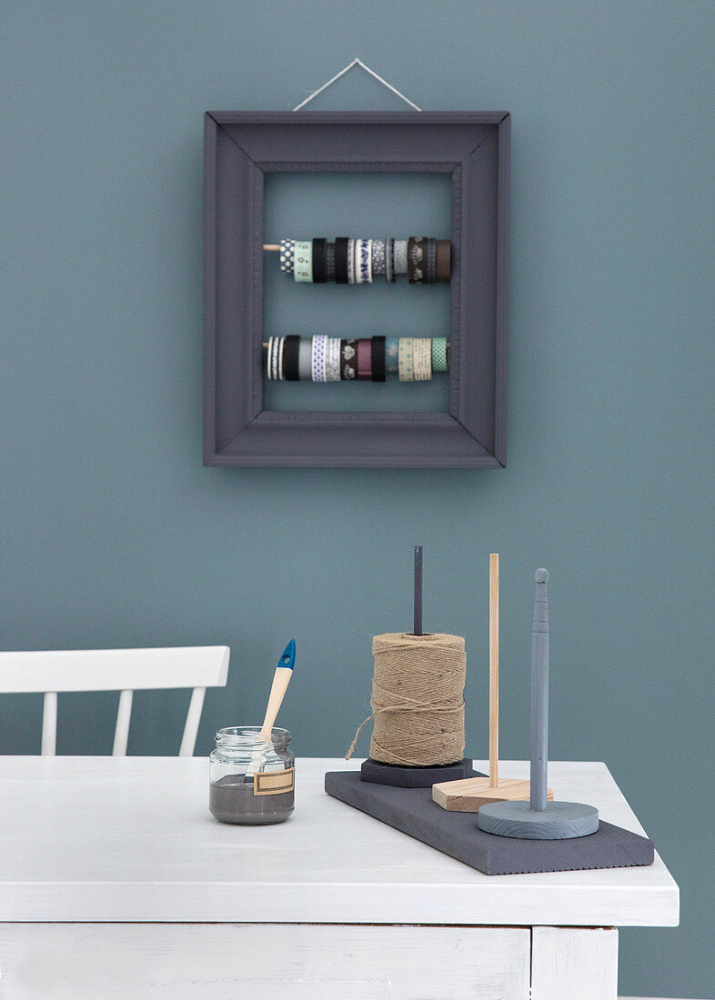 Picture frame with rods for storing masking tape and board with spool holders