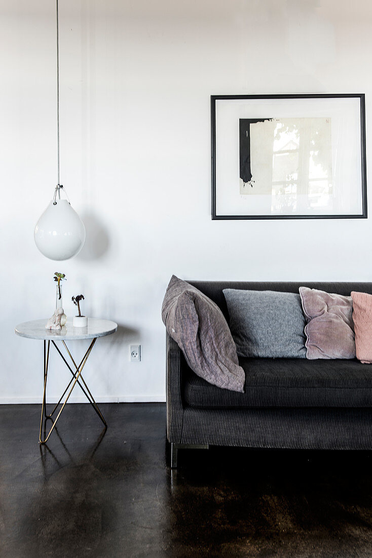Gray upholstered sofa with cushions, side table, above a pendant lamp in the living room