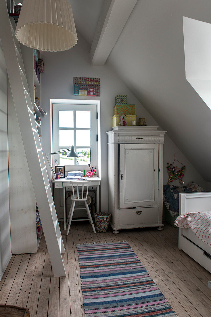 Wooden cupboard and small desk in a girls' room in the attic