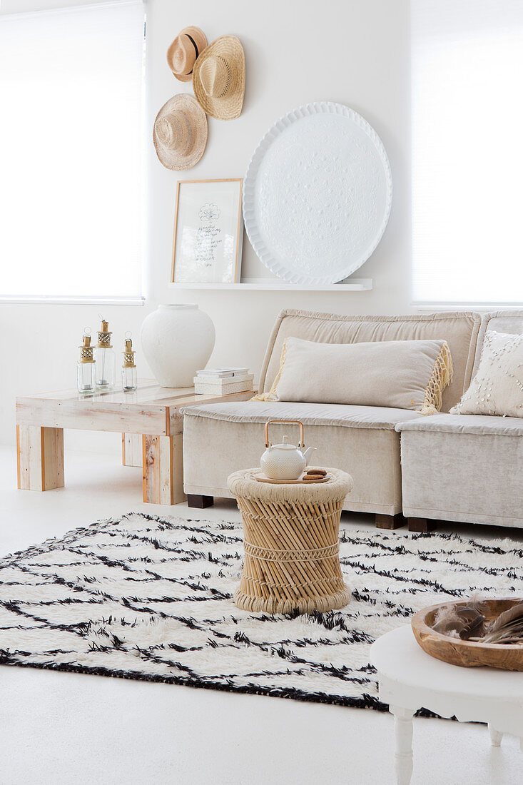 A side table on a diamond patterned rug with a sofa in a light living room