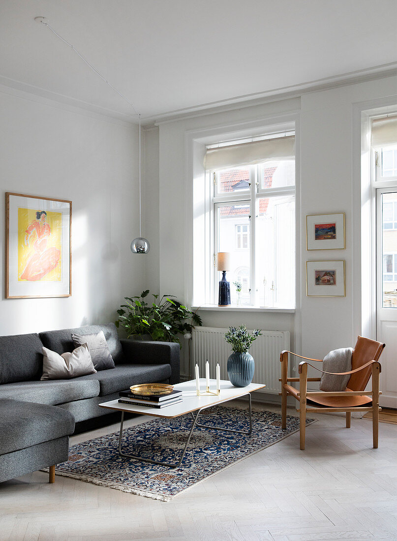 A grey sofa and a leather chair in a simple living room with a white floor
