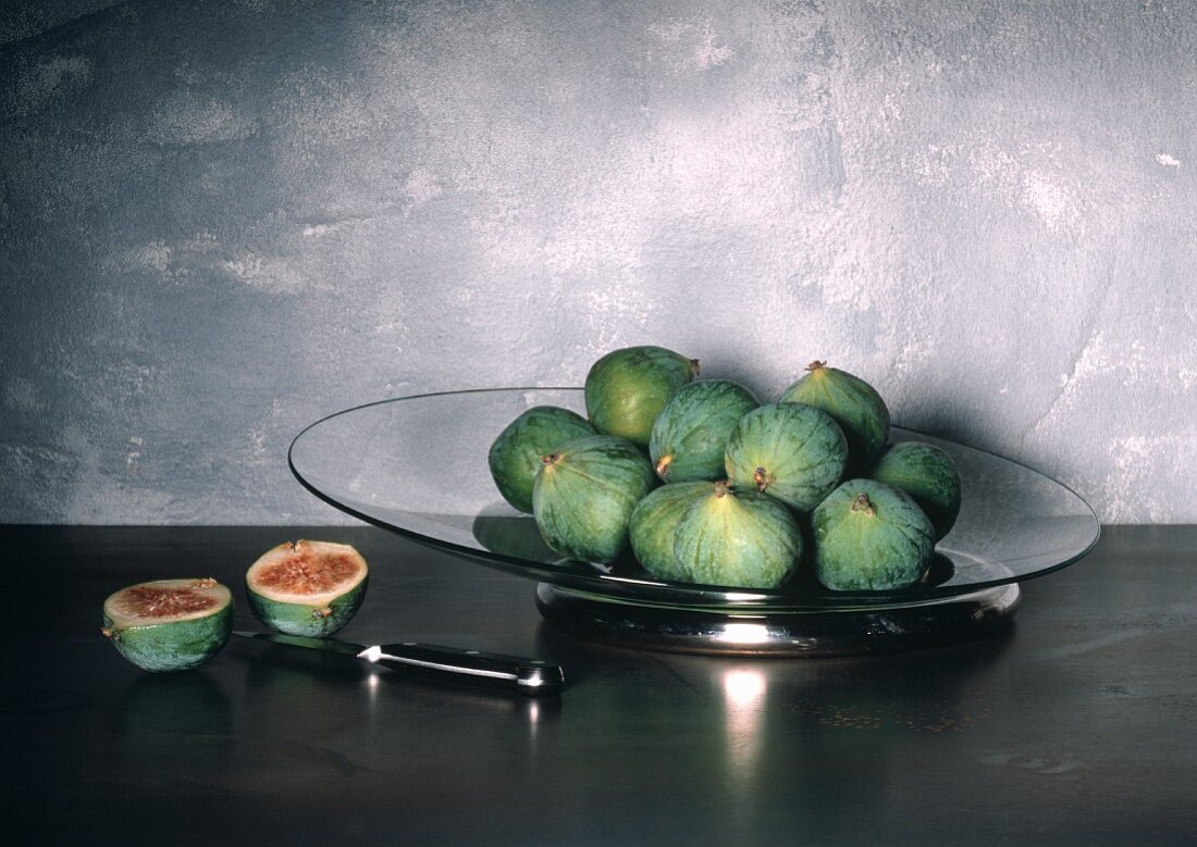 Whole Fresh Figs on a Glass Plate and a Halved Fig; Knife