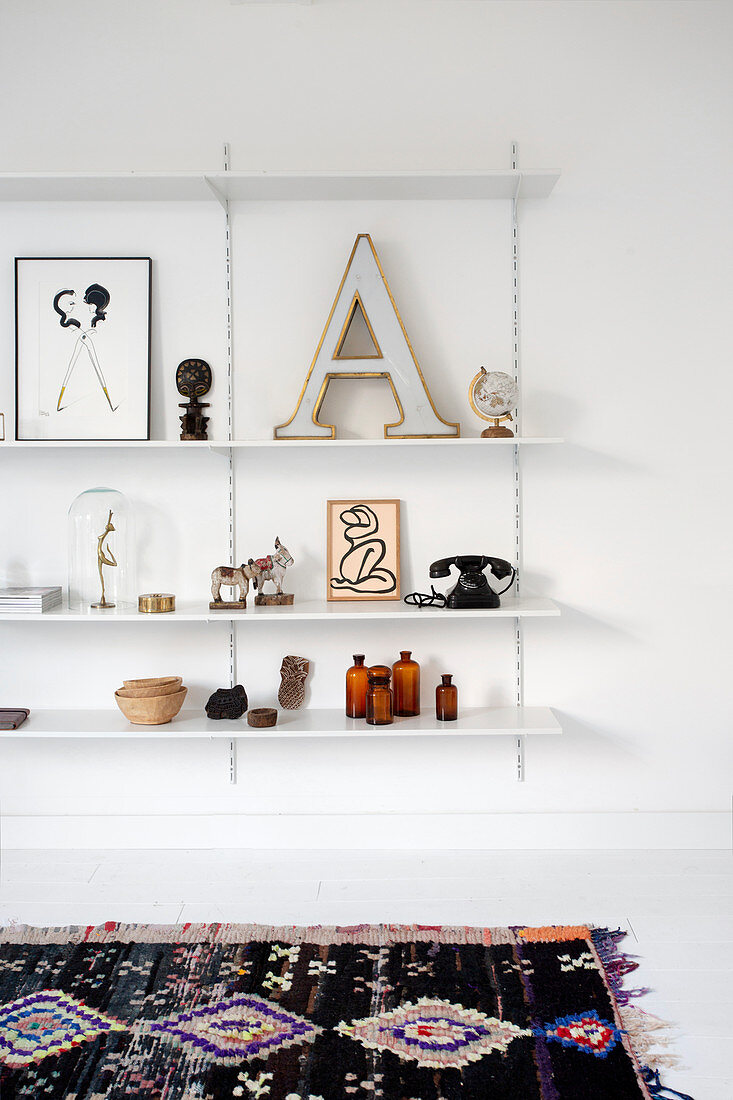 A letter and vintage decoration on a wall shelf with an old colourful rug