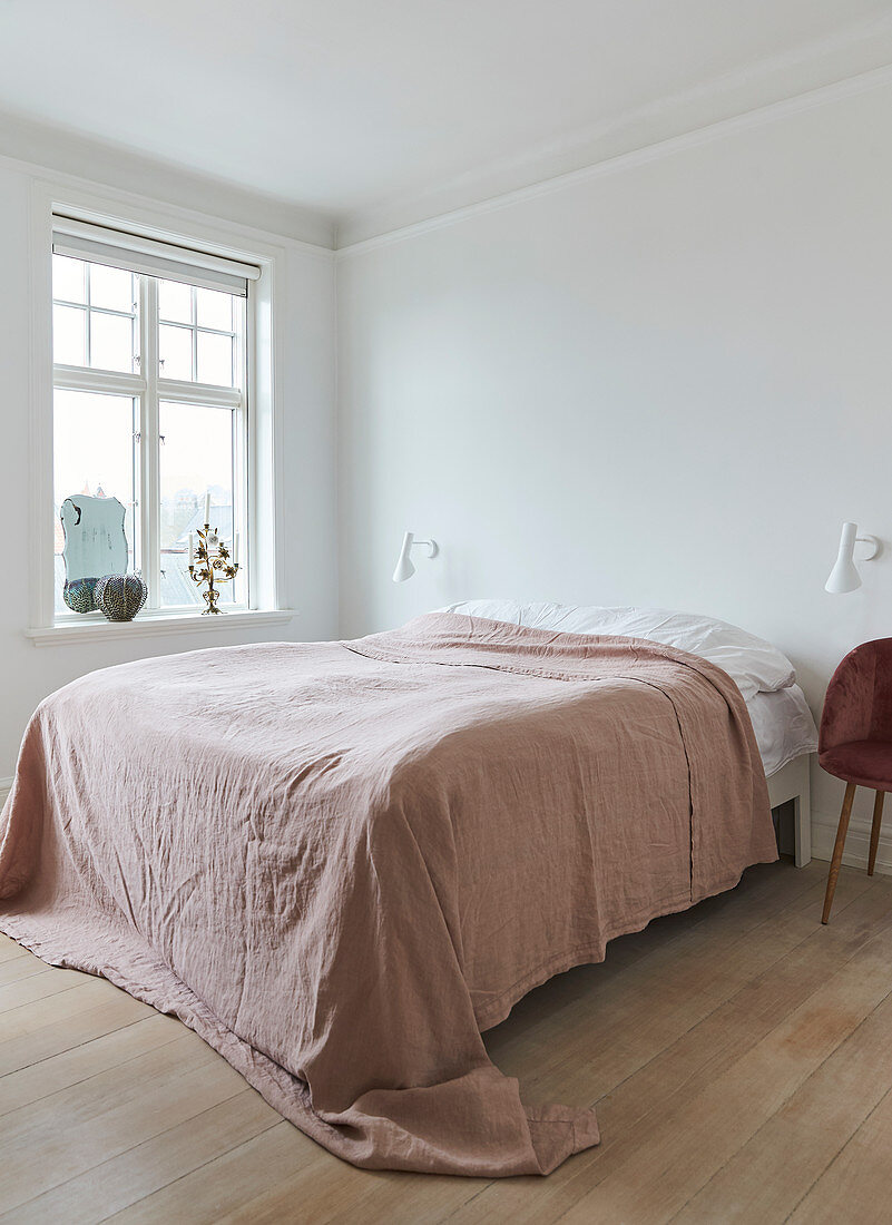 Doppelbett mit Tagesdecke in hellem Schlafzimmer