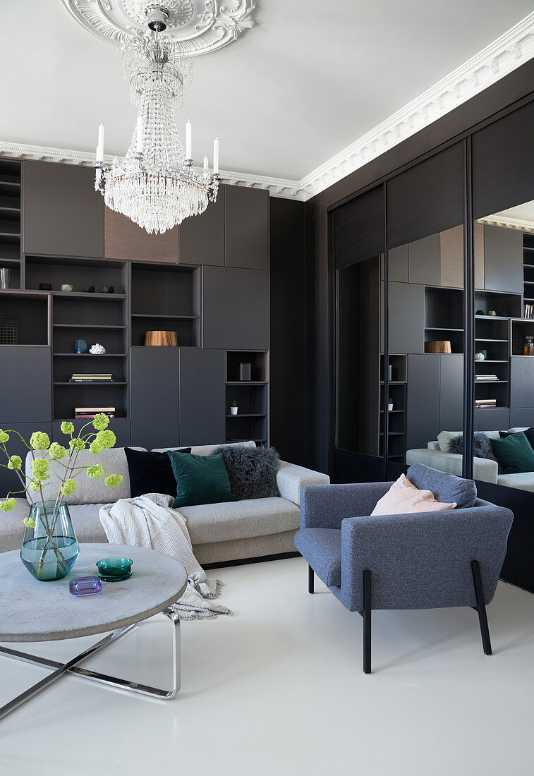 Dark living room wall, upholstered furniture, round coffee table and chandelier