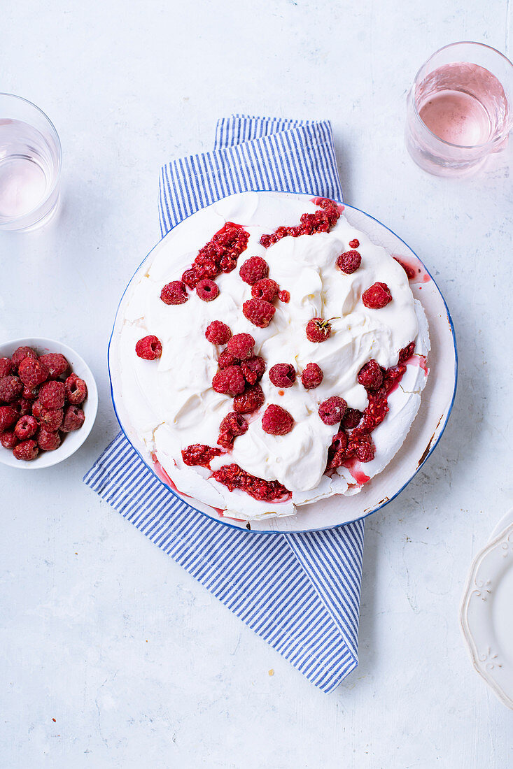 Pavlova meringue cake with whipped cream and fresh raspberries