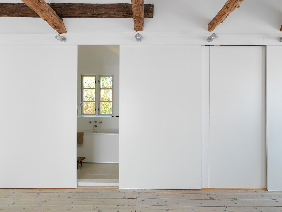 A hallway with wooden beams and sliding doors leading to a bathroom